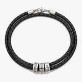 Pulseira Cordão da Família em couro preto com contas gravadas, fundo cinzento